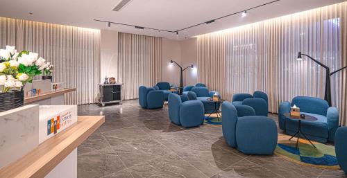 a waiting room with blue chairs and flowers at Ewaa Express Hotel - Yanbu Alamarah in Yanbu