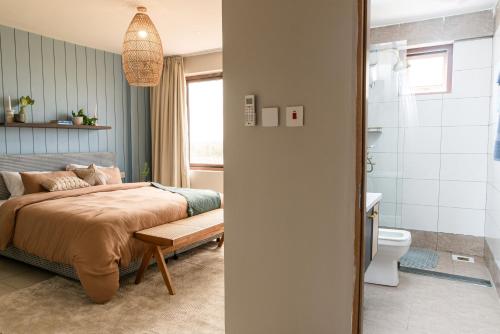 a bedroom with a bed and a bathroom with a toilet at Sandy Shore Beach Apartments - Karibu Quarters in Kikambala