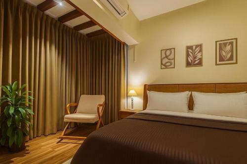 a hotel room with a bed and a chair at Cairo in Siolim