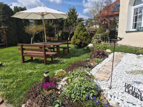 a park bench with an umbrella in a garden at Willa Helena in Cisna