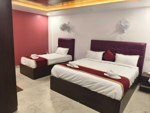 two beds in a hotel room with red walls at Yercaud Rathna Residency in Yercaud
