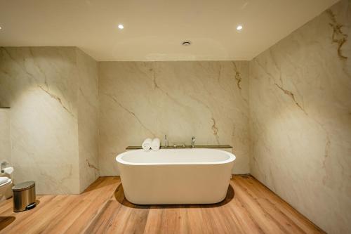 a white bath tub in a bathroom with a sink at ACASA Collective in Aurangabad