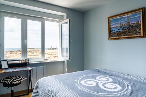 a bedroom with a bed and a view of the beach at La Rose des Mers in Tréffiagat