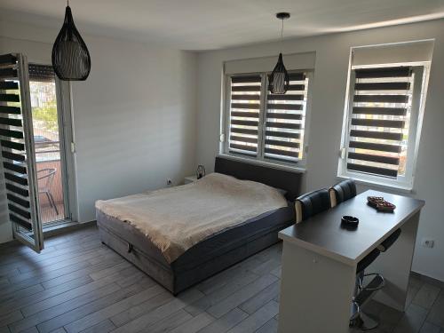 a bedroom with a bed and a desk and windows at DANICA in Sremska Mitrovica