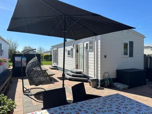 Ein schwarzer Sonnenschirm auf einer Terrasse mit Tisch und Stühlen in der Unterkunft J 171 in Petten