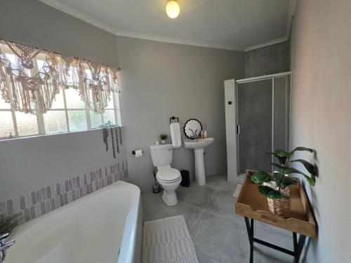 a bathroom with a tub and a toilet and a sink at Grey Crescent living in Welkom