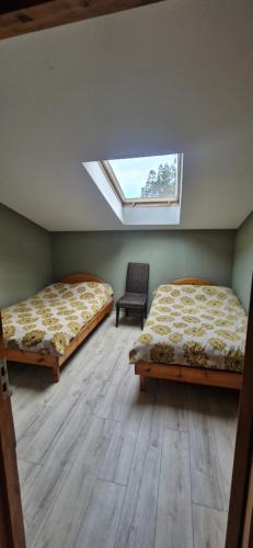 zwei Betten in einem Zimmer mit Fenster und einem Stuhl in der Unterkunft Lejupes in Plānupe