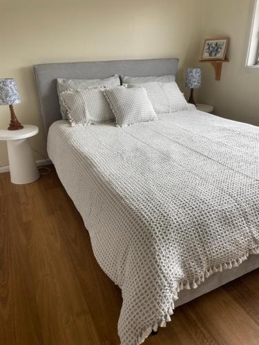 a bedroom with a bed with a white comforter at 3 bedroom Creswell Street Cottage - Pet Friendly in West Wyalong