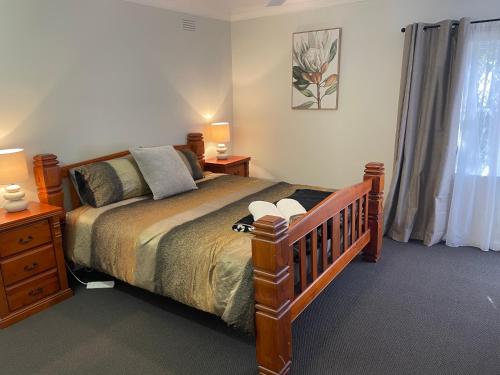 a bedroom with a bed and two night stands and a window at Easy Wagga Stopover, Spacious & Comfortable in Forest Hill