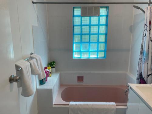 a bathroom with a pink tub and a window at Easy Wagga Stopover, Spacious & Comfortable in Forest Hill