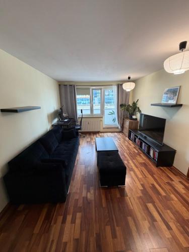 a living room with a black couch and wooden floors at Elegancki apartament w centrum in Warsaw