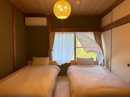 two beds in a room with a window at 近露の家 -chikatsuyunoie- in Tanabe