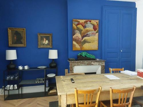 a blue room with a table and a painting on the wall at Le Palais Des Marins in Châteauroux
