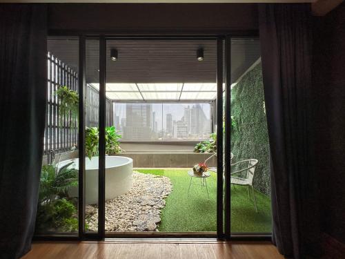 a room with a large glass door with a bath tub at G Boutique Silom Hotel in Bangkok