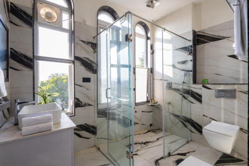 a bathroom with a glass shower and a toilet at Jolawas Stays Udaipur in Udaipur