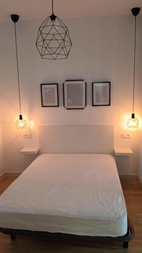 a bedroom with a bed with three pictures on the wall at SG Estudios Sanlúcar in Sanlúcar de Barrameda