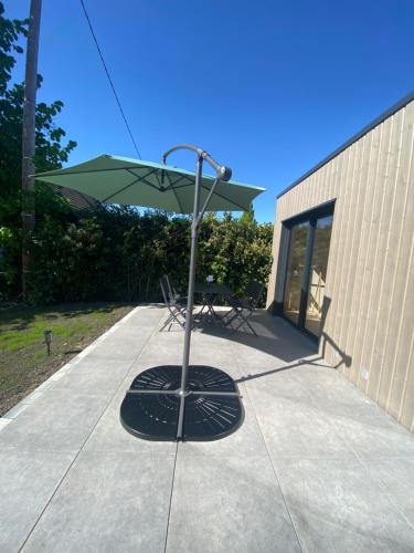 a green umbrella sitting on a concrete sidewalk at Au loft, micro maison vue sur prairie in Rohrwiller