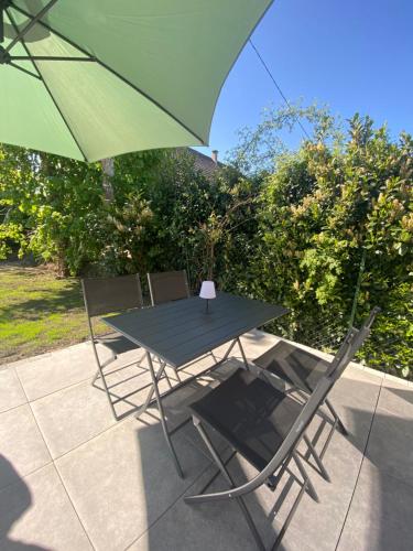 a table and two chairs with a green umbrella at Au loft, micro maison vue sur prairie in Rohrwiller