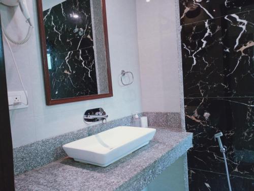 a bathroom with a white sink and a black marble wall at Hotel Aerotech Near Delhi Airport in New Delhi