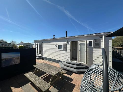 ein Mobilheim mit Tisch und Stühlen auf einer Terrasse in der Unterkunft J 171 in Petten