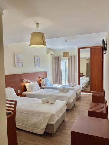 a group of four beds in a hotel room at Hospedaria Buganvilia Alvor in Alvor