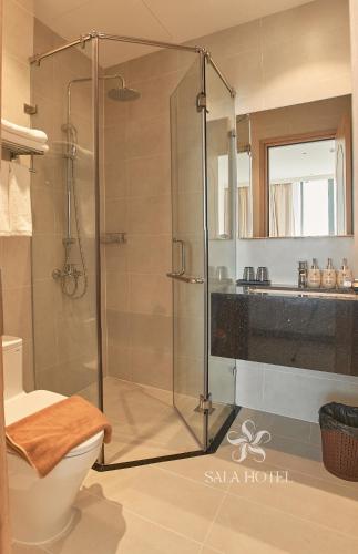 a bathroom with a shower with a toilet and a sink at Sala Hotel Phan Thiet in Phan Thiet