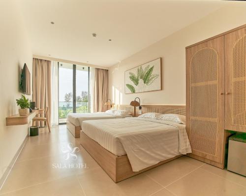 a bedroom with two beds and a large window at Sala Hotel Phan Thiet in Phan Thiet