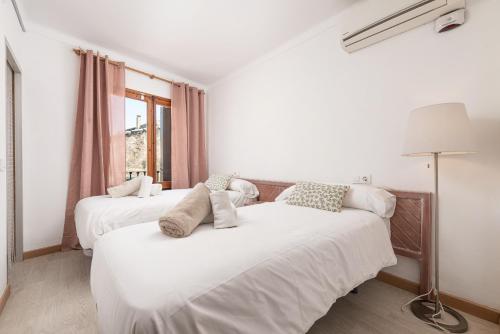 two beds in a white room with a window at Can Calco old town in Alcudia