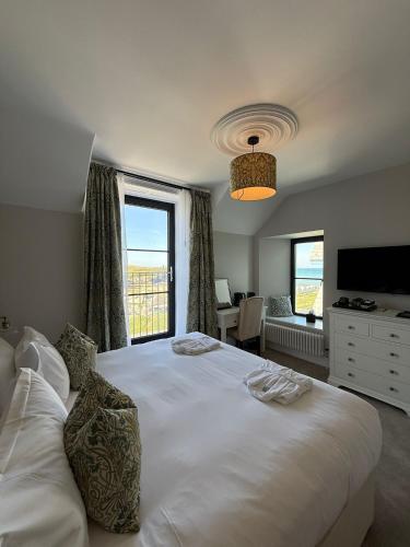 a bedroom with a large white bed with a window at The Edge Of The Beach in Bude