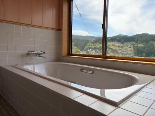 a large bath tub in a bathroom with a window at 近露の家 -chikatsuyunoie- in Tanabe