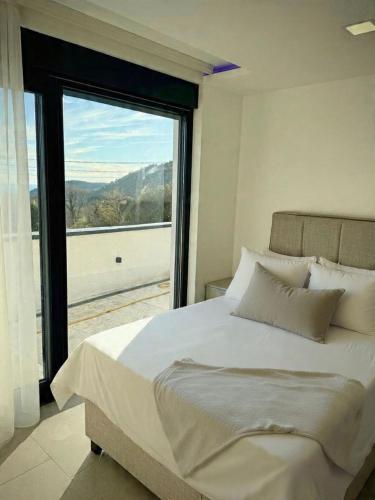 a bedroom with a large bed with a large window at Villa Maja in Sutomore