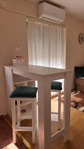 a white table with two stools and a fan at Apartman Lavanda in Temerin