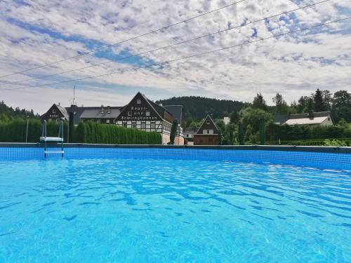 a large blue swimming pool in front of a house at Naturhotel Lindenhof in Rechenberg-Bienenmühle