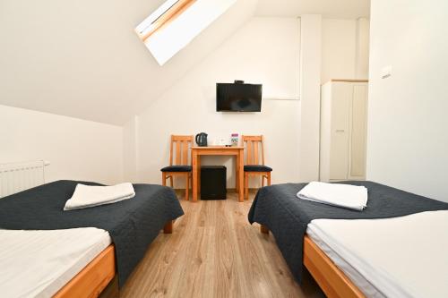 two beds in a room with a desk and a tv at Marina Grudziądz in Grudziądz