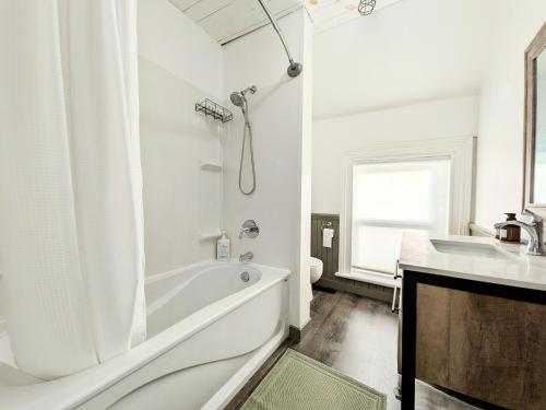 a white bathroom with a tub and a sink at Red Roof Guesthouse in Cobourg