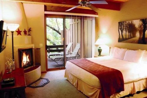 a bedroom with a bed and a fireplace and a balcony at Junipine Resort in Sedona