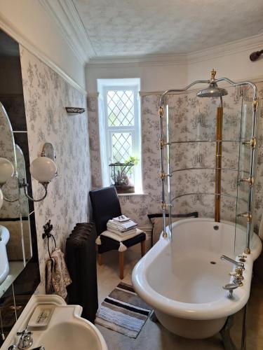 a bathroom with a large tub and a chair at Moon River in Goodwick