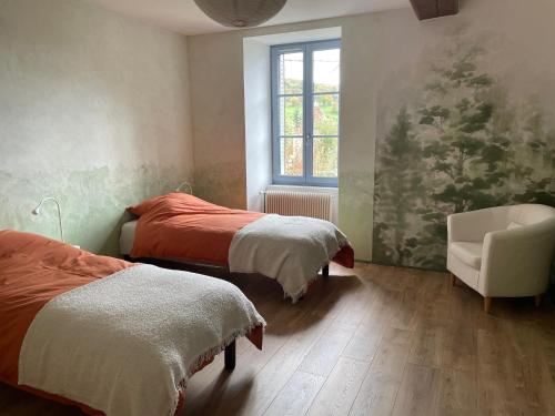 a bedroom with two beds and a chair and a window at Cense des Possibles, Forêt et Prairie in Darcey