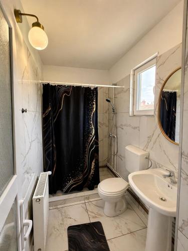 a bathroom with a black shower curtain and a toilet at Casa Marinca in Ocna Şugatag