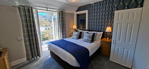 a bedroom with a bed and a large window at Derrybeg Bed and Breakfast in Pitlochry