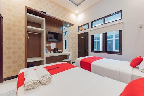 a bedroom with two beds and a tv at RedDoorz Plus at Orange Diponogoro Palangkaraya in Palangkaraya