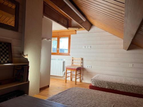 a bedroom with two beds and a chair in a room at Chalet confort avec cheminée in Camprieu
