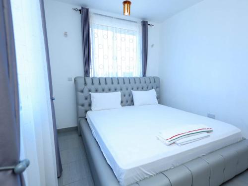 a white bed in a room with a window at Kenya coast stays in Nyali