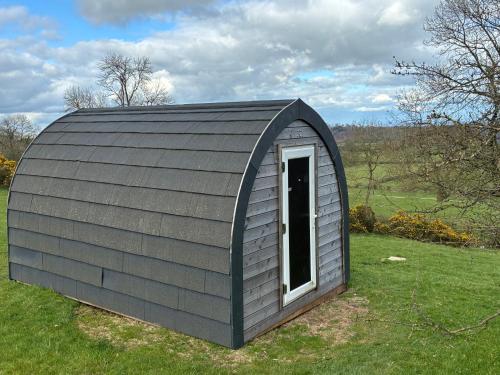 a small shed with a door in a field at Hillside Pod in Oswestry