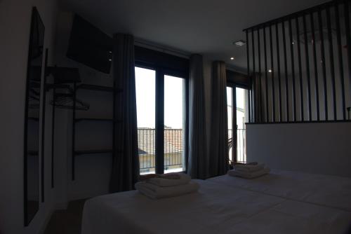 a bedroom with two beds and a large window at IG Apartamentos in Palas de Rei