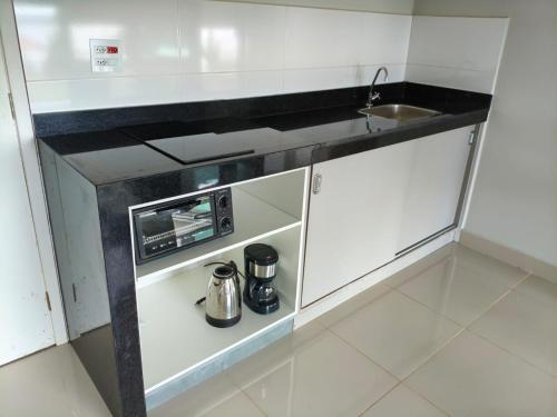 a small white kitchen with a sink and a microwave at Lazer , Descanso, Pesca e Praia in Iguape