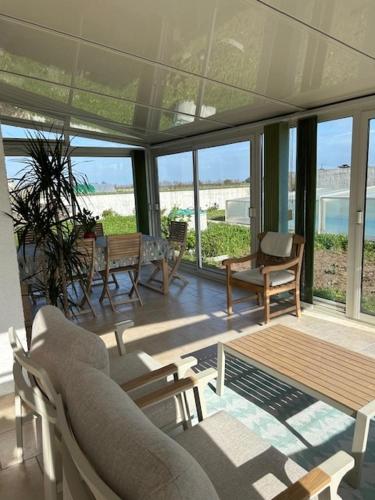 a living room with chairs and a table and windows at Terredesel Oleron in Saint-Denis-dʼOléron