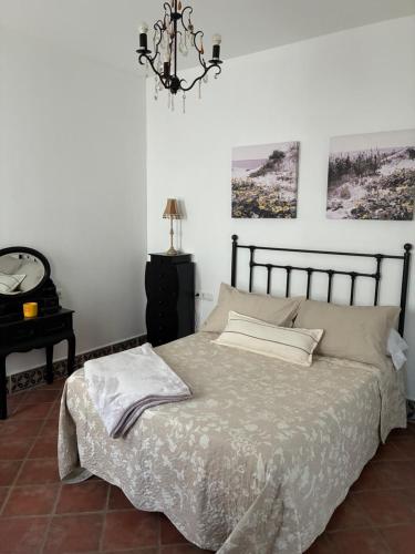 a bedroom with a bed and a chandelier at Casa Las Adelfas in Isla Cristina