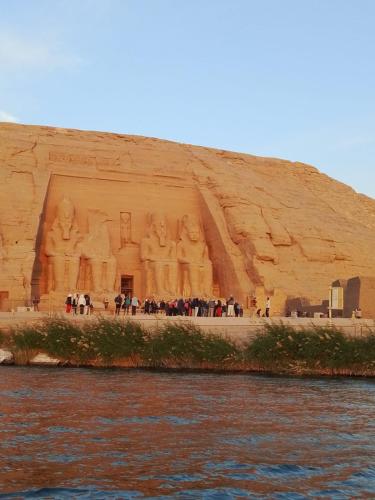 a group of people standing in front of a large building at sunset in Abu Simbel