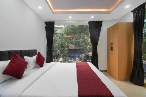 a bedroom with a large bed with red pillows and a window at Hotel Royal City Palace in Kolkata